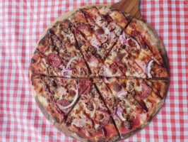 Delicious meat lover's pizza with pepperoni, ham, and bacon, topped with cheese and onions.
