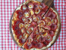 Delicious pepperoni pizza with melted cheese on a wooden serving board.